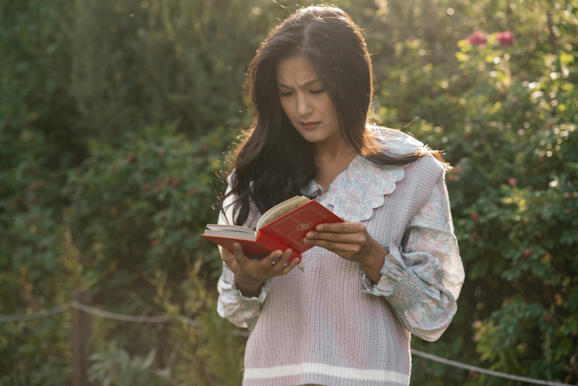 woman standing in the garden reading a book